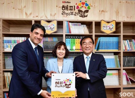 4일 오후 충북 청주시 서원구 &lsquo;행복나무지역아동센터&rsquo;에서 열린 오비맥주 &lsquo;해피 라이브러리&rsquo; 완공 기념식에 참석한 김도훈 오비맥주 사장(왼쪽)과 신희경 행복나무지역아동센터장(가운데), 이승훈 청주시장(오른쪽)이 현판식에 앞서 기념 촬영을 하고 있다.