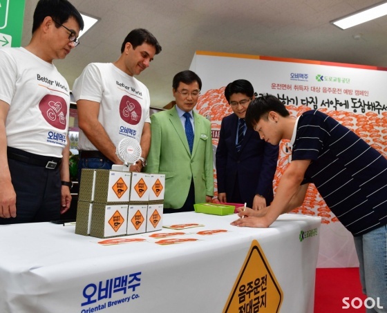 오비맥주가 21일 도로교통공단과 함께 서울 강남운전면허시험장에서 신규 운전면허취득자를 대상으로 음주운전 예방 캠페인을 펼쳤다.(왼쪽부터) 장유택 오비맥주정책홍보 부사장, 김도훈 오비맥주대표,김선호 강남운전면허시험장장,우진구 도로교통공단 홍보처장이  &lsquo;음주운전 안하기다짐 서약&rsquo; 활동을 안내하고 있다.