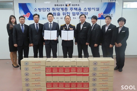 22일 부산 동래소방서 표승완 서장(가운데 오른쪽)과 대선주조 조우현 대표(가운데 왼쪽)가 협약서를 들고 양측 관계자들과 함께 저소득층 주택화재 예방 협력을 약속했다.