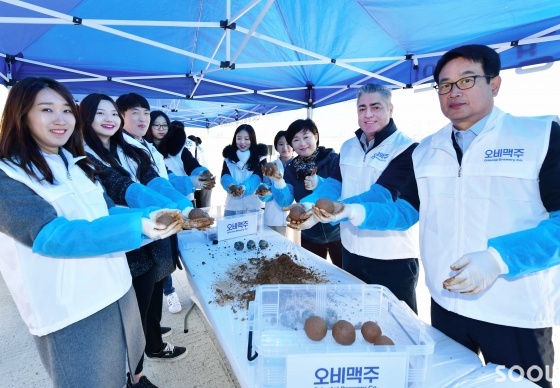 22일 오비맥주 고동우 대표(오른쪽에서 두 번째), 정책홍보부문 장유택 부사장(오른쪽에서 첫 번째)과 임직원들이 서울 강남 탄천에서&lsquo;세계 물의 날&rsquo;을 기념해 수질 개선에 도움이 되는 흙공을 직접 만들고 있다.