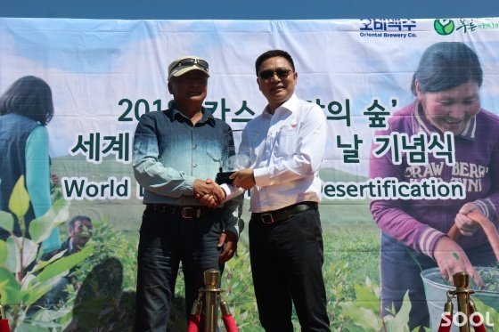 13일 몽골 주민 대표(왼쪽)가 AB인베브 아시아태평양 프랭크왕 부사장(오른쪽)에게 몽골환경난민들의 자립지원과 환경복원사업에 대한 고마움의 표시로 감사패를 전달하고 있다.